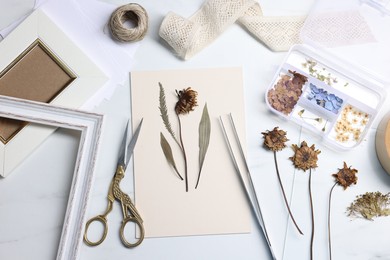 Photo of Flat lay composition with dry flowers and paper on white marble table
