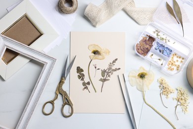 Photo of Flat lay composition with dry flowers and paper on white marble table