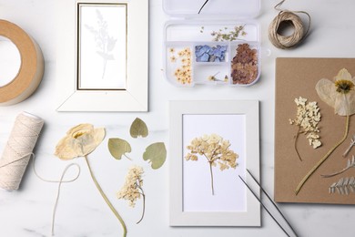 Photo of Flat lay composition with dry flowers and picture frames on white marble table