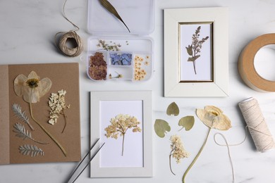 Photo of Flat lay composition with dry flowers and picture frames on white marble table