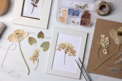 Photo of Flat lay composition with dry flowers and picture frames on white marble table