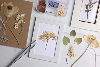 Photo of Flat lay composition with dry flowers and picture frames on white marble table