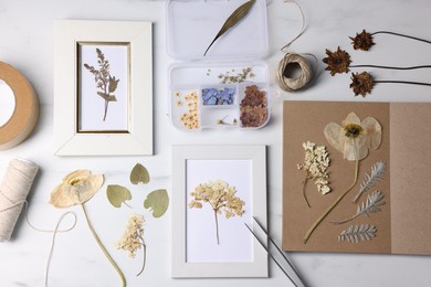 Photo of Flat lay composition with dry flowers and picture frames on white marble table