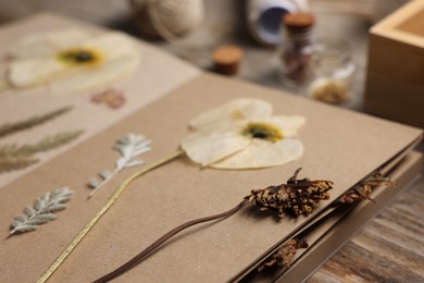 Photo of Dry flowers, leaves and notebook on wooden table, closeup