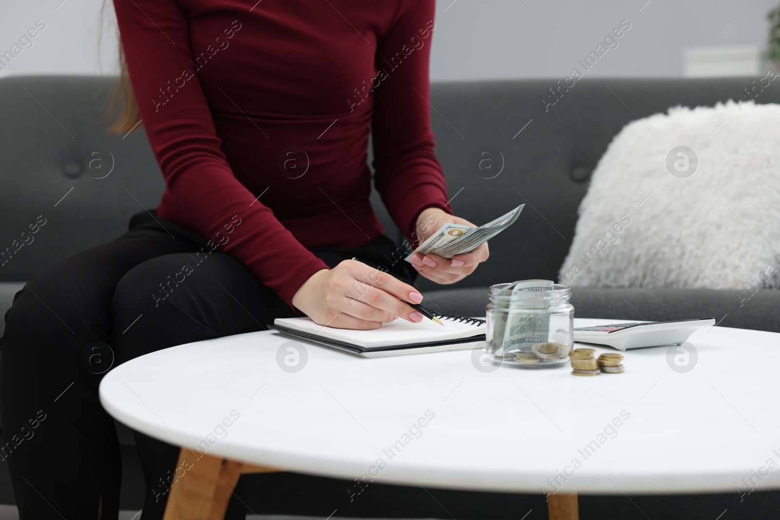 Photo of Woman counting dollar banknotes on sofa indoors, closeup