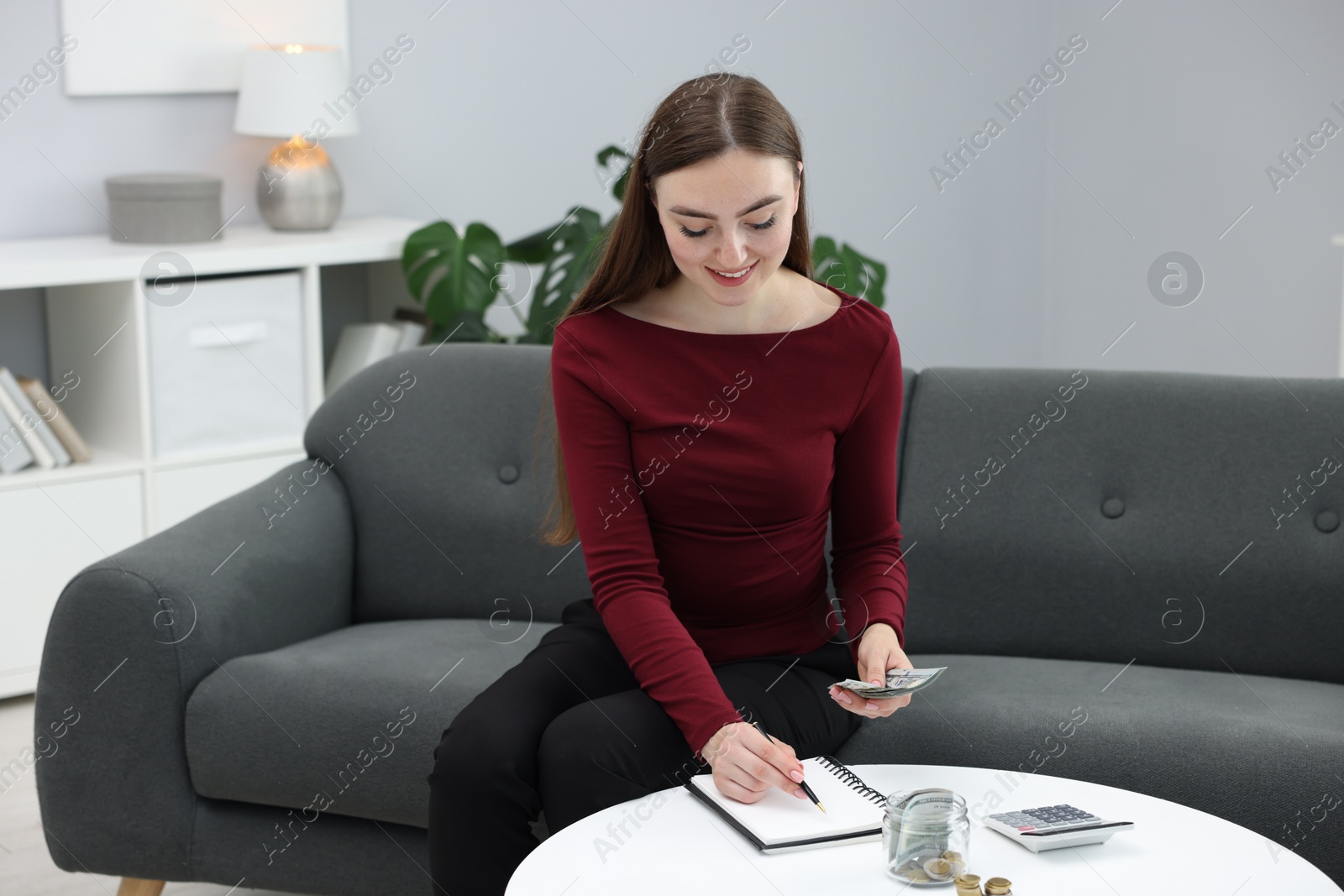 Photo of Woman counting dollar banknotes on sofa indoors