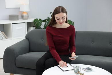 Photo of Woman counting dollar banknotes on sofa indoors