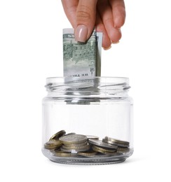 Photo of Woman putting dollar banknote into glass jar on white background, closeup