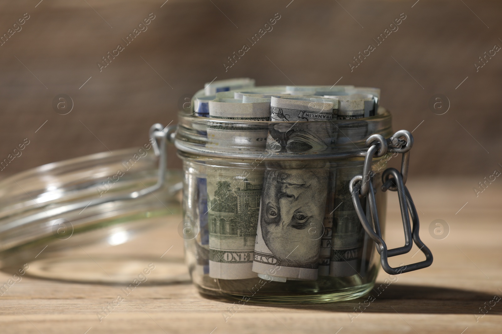Photo of Glass jar with dollars on wooden table, closeup