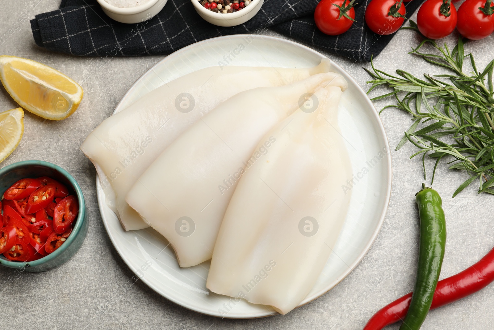 Photo of Pieces of raw squids, spices and products on grey textured table, flat lay