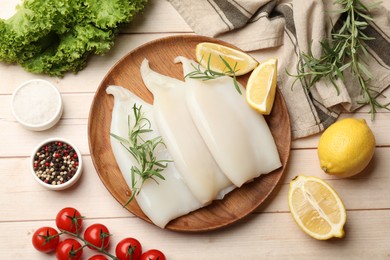 Photo of Pieces of raw squids with products and spices on light wooden table, flat lay