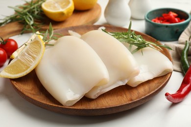 Photo of Pieces of raw squids with products on white table, closeup