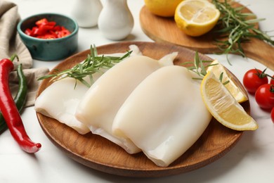 Photo of Pieces of raw squids with products on white table, closeup