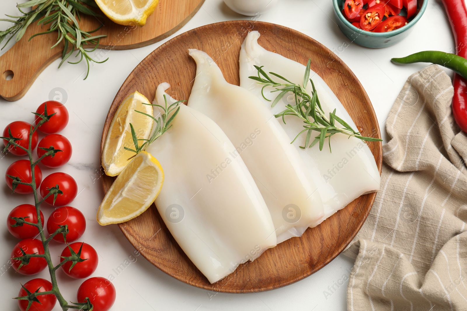 Photo of Pieces of raw squids with products on white table, flat lay