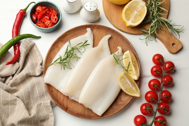 Photo of Pieces of raw squids with products and spices on white table, flat lay