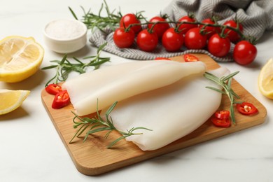 Photo of Pieces of raw squids and products on white table, closeup