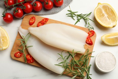 Photo of Pieces of raw squids and products on white table, flat lay