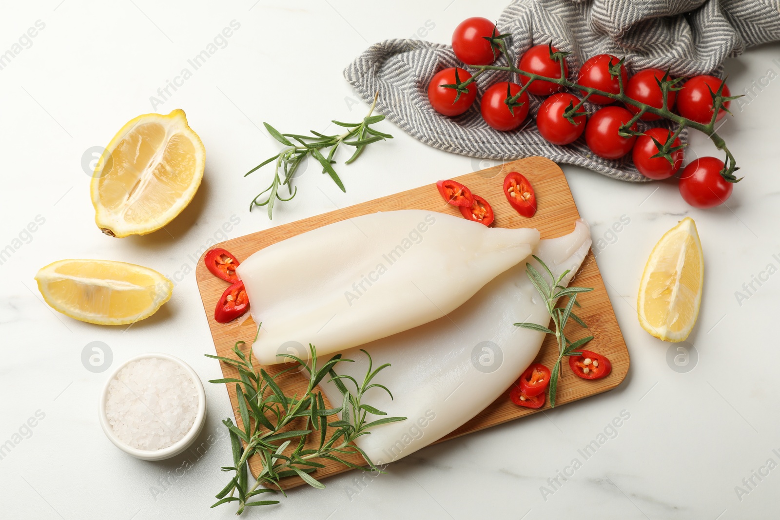 Photo of Pieces of raw squids and products on white table, flat lay