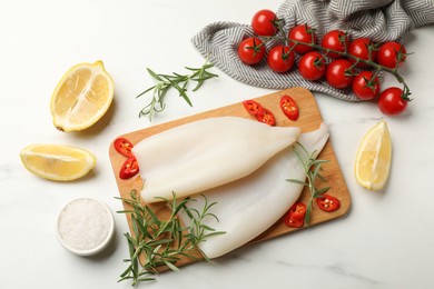 Photo of Pieces of raw squids and products on white table, flat lay