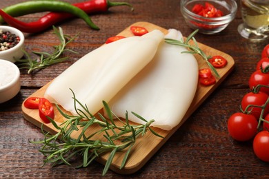 Photo of Pieces of raw squids and products on wooden table, closeup