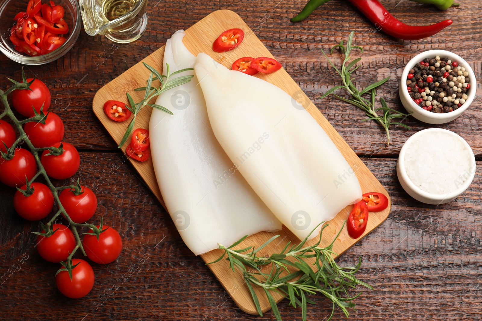 Pieces of raw squids, products and spices on wooden table, flat lay Photo of Pieces of raw squids, products and spices on wooden table, flat lay