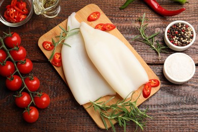 Photo of Pieces of raw squids, products and spices on wooden table, flat lay