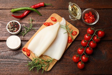 Photo of Pieces of raw squids, products and spices on wooden table, flat lay