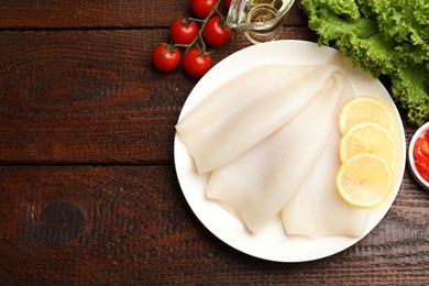 Photo of Pieces of raw squids and products on wooden table, flat lay. Space for text