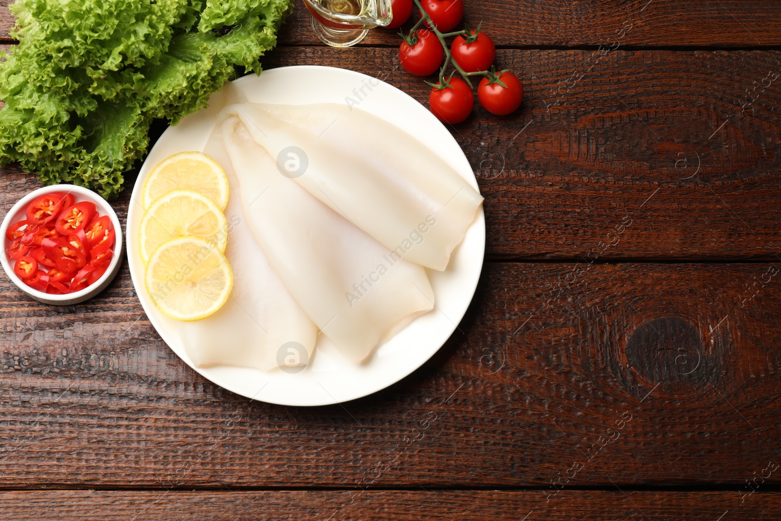 Pieces of raw squids and products on wooden table, flat lay. Space for text Photo of Pieces of raw squids and products on wooden table, flat lay. Space for text