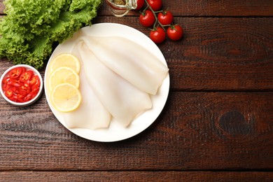 Photo of Pieces of raw squids and products on wooden table, flat lay. Space for text