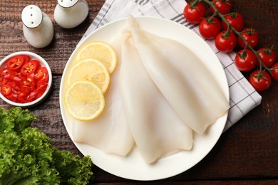 Photo of Pieces of raw squids, spices and products on wooden table, flat lay