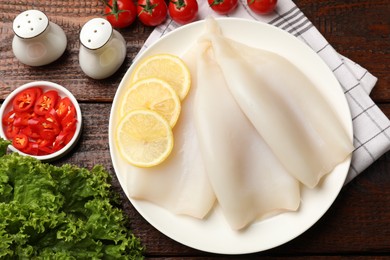 Photo of Pieces of raw squids, spices and products on wooden table, flat lay