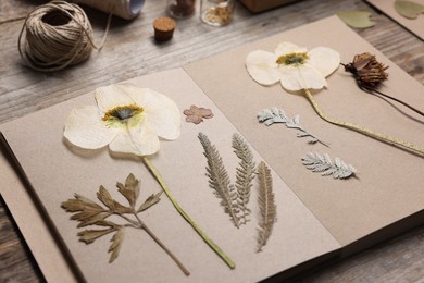 Photo of Dry flowers, leaves and notebook on wooden table, closeup