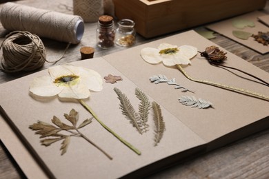 Photo of Dry flowers, leaves and notebook on wooden table, closeup