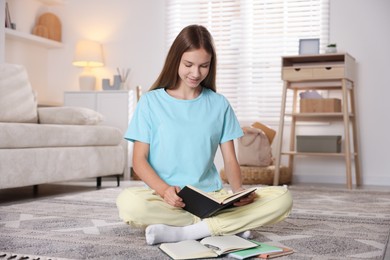 Photo of Teenage girl studying with books on floor at home