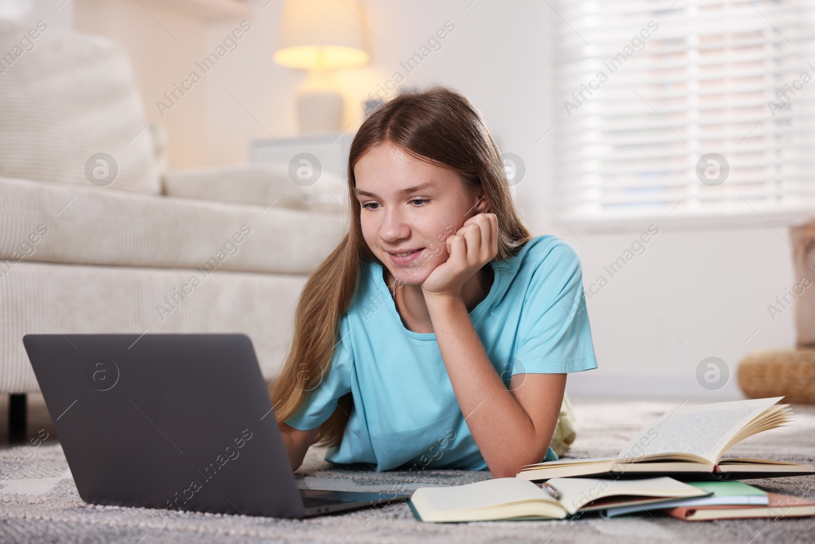 Photo of Teenage girl studying online on floor at home