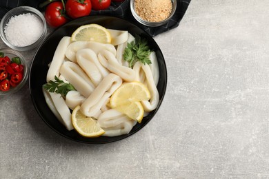 Photo of Raw squid rings, lemon, parsley, spices and products on grey textured table, flat lay. Space for text