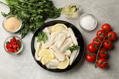 Photo of Raw squid rings, lemon, parsley, spices and products on grey textured table, flat lay