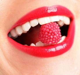 Photo of Woman with beautiful lips makeup and raspberry candy, closeup