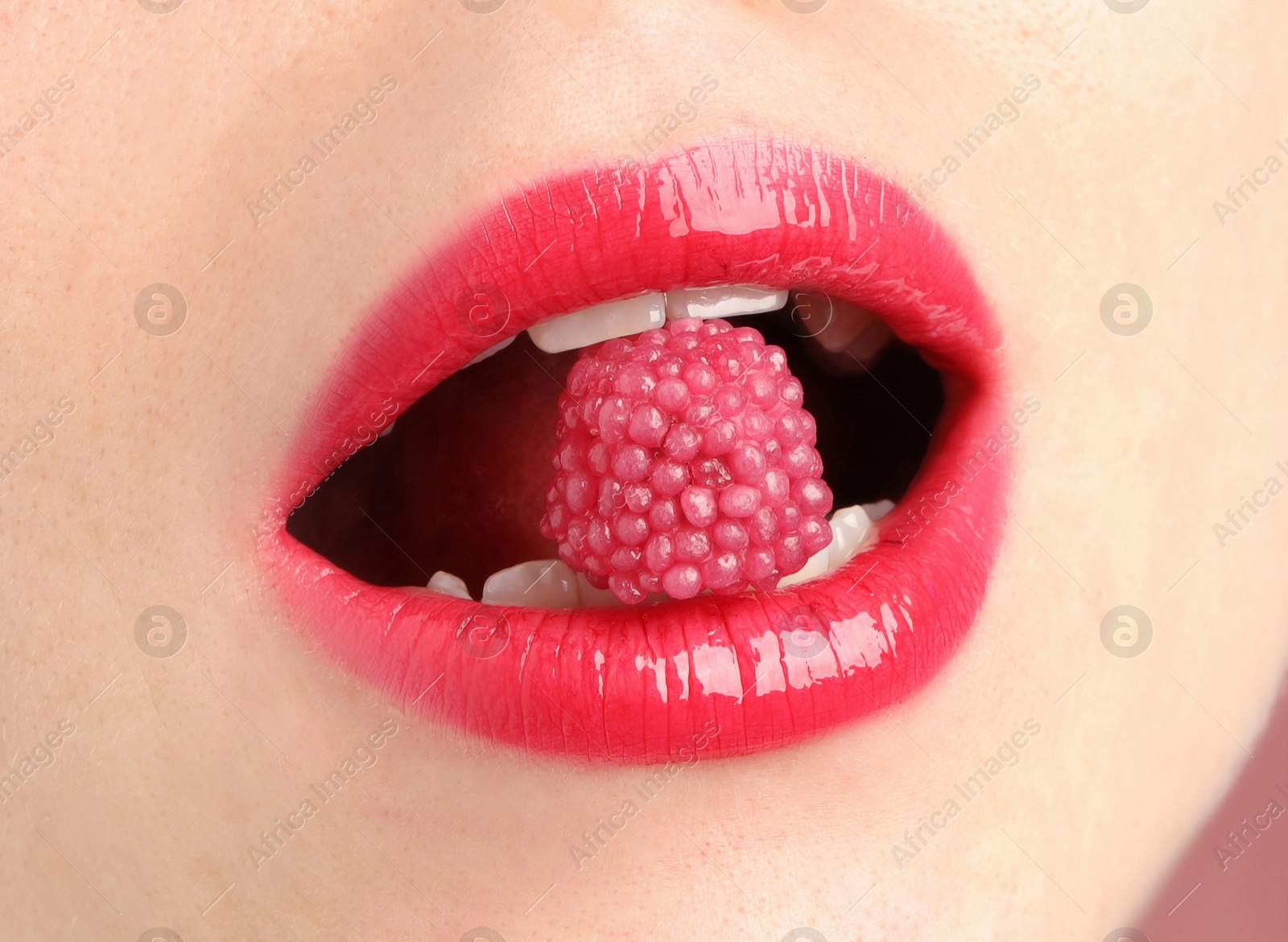 Photo of Woman with beautiful lips makeup and raspberry candy, closeup