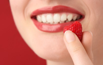 Photo of Woman with beautiful lips makeup and raspberry on red background, closeup