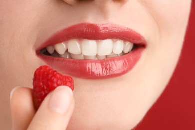 Photo of Woman with beautiful lips makeup and raspberry on red background, closeup