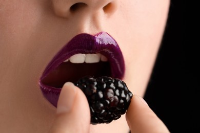 Photo of Woman with beautiful lips makeup and blackberry on black background, closeup