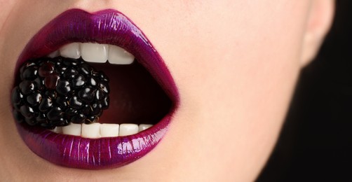 Photo of Woman with beautiful lips makeup and blackberry on black background, closeup
