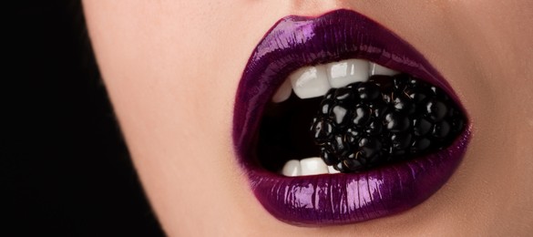 Photo of Woman with beautiful lips makeup and blackberry on black background, closeup