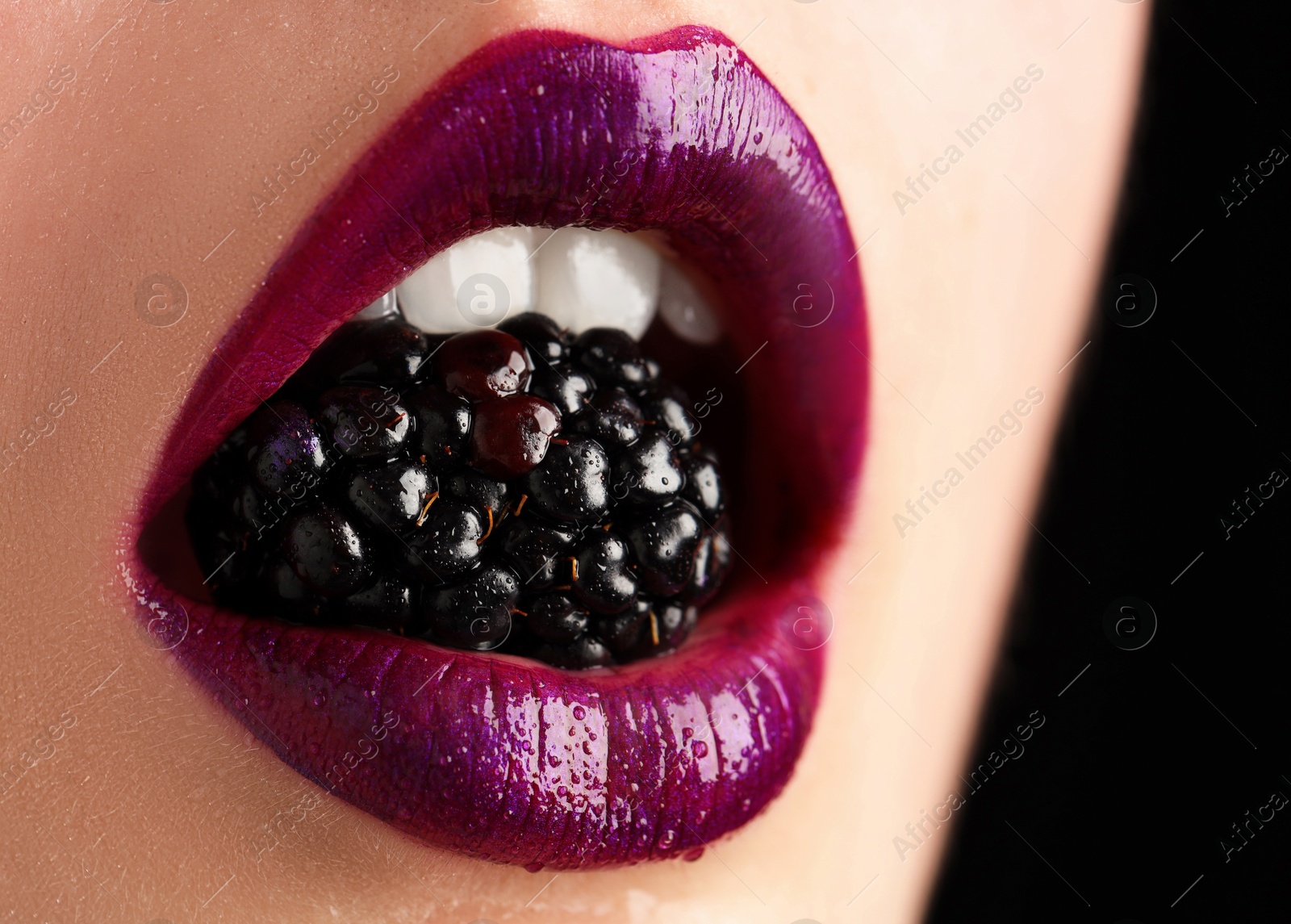 Photo of Woman with beautiful lips makeup and blackberry on black background, closeup