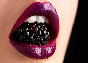 Photo of Woman with beautiful lips makeup and blackberry on black background, closeup