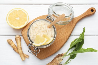 Photo of Tasty horseradish sauce with lemon slices and roots on white wooden table, flat lay