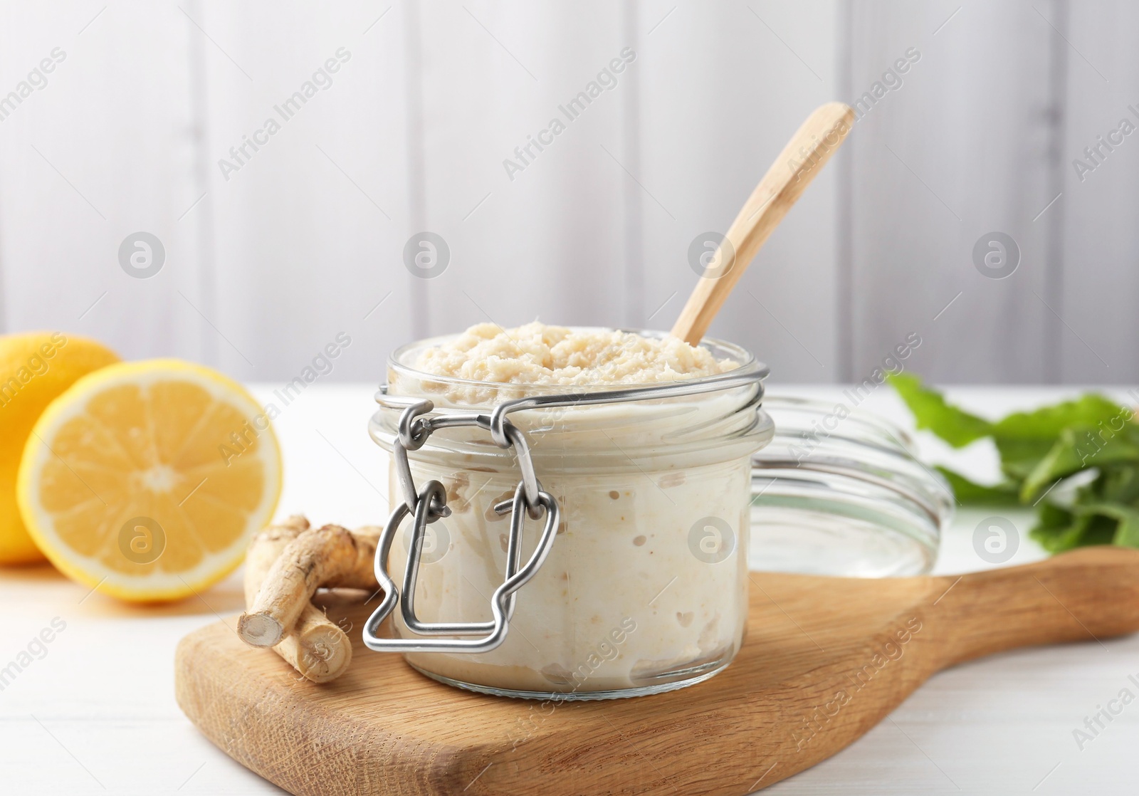 Photo of Tasty horseradish sauce, roots and lemons on white wooden table, closeup