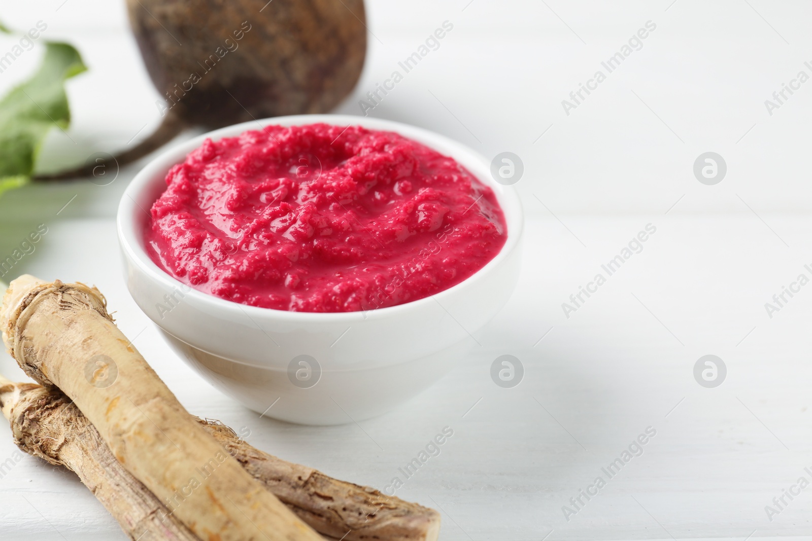 Tasty horseradish sauce with beetroot, vegetable and roots on white wooden table, closeup. Space for text Photo of Tasty horseradish sauce with beetroot, vegetable and roots on white wooden table, closeup. Space for text